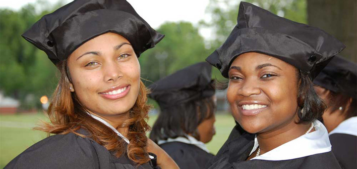 Two smiling female Bennett College graduates pose for a photo after commencement ceremony.