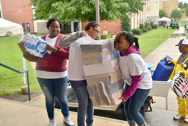 Incoming freshmen girls struggle to bring several boxes of shoes up stairs at the entrance of their dorm at North Carolina A&T State University.