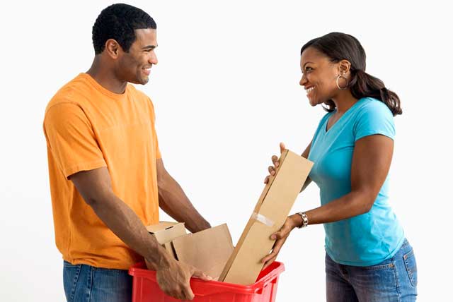 African American male college student holds a bin while pretty female puts cardboard into it for winter break jobs.