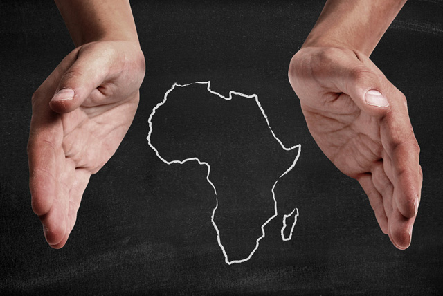 African Diaspora: Black hands supporting chalk drawn image of Africa.