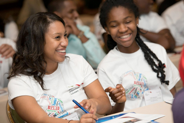 Two female African American students enjoy listening to a guest speaker at the 2013 Gates Millennium Scholars CA Freshman Leadership in California. Applications are open for the Bill Gates Scholarship through January 14, 2015.