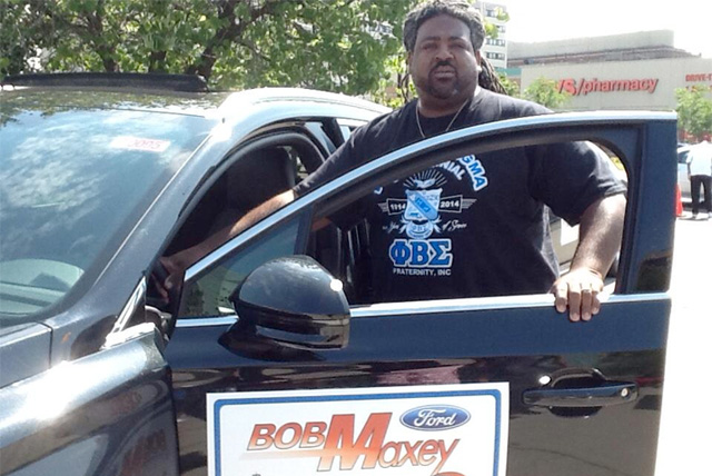 A Phi Beta Sigma Fraternity member poses with a Lincoln Motors vehicle at the 2014 Divine Nine Driven To Give Program event in Detroit, MI on Aug. 16th.