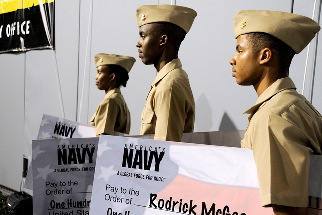 Three students holding big paper checks receive NROTC scholarships.