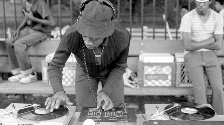 Image of old school Hip-Hop DJ, who is mixing and scratching on two turn tables.