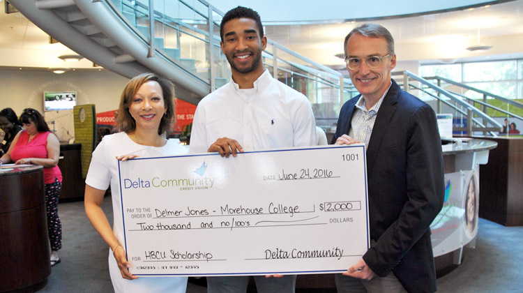 Delmer Jones III holds a giant scholarship check with KISS 104 radio personality Veronica Waters and Delta Community Credit Union C.O.O. Matthew Shepherd