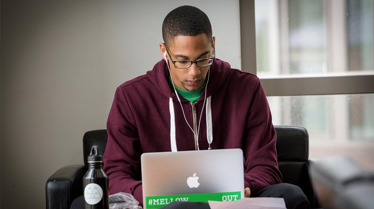 A male student applies for the HBCU CONNECT Minority Scholarship Program online while sitting in the campus library.