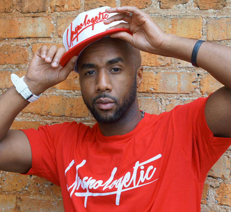 Brian "B-Phraze" Frazier, a 2015 John Lennon Songwriting Contest winner poses wearing red and white "unapologetic" gear.