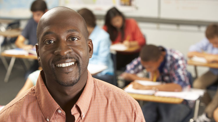 Education programs: Portrait of a Black male teacher in a classroom.