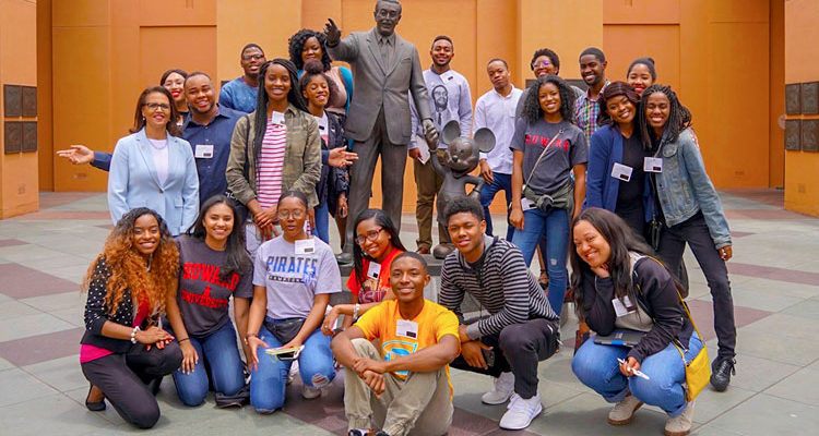 HBCU In LA Internship participants poses in front of a statue of Walt Disney Holding Mickey's hand at the Walt Disney Animation Studios in Burbank, CA during the HBCU Hollywood Welcome week.
