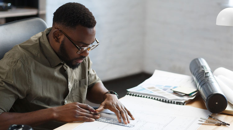 Afro-American architect working in office with blueprints